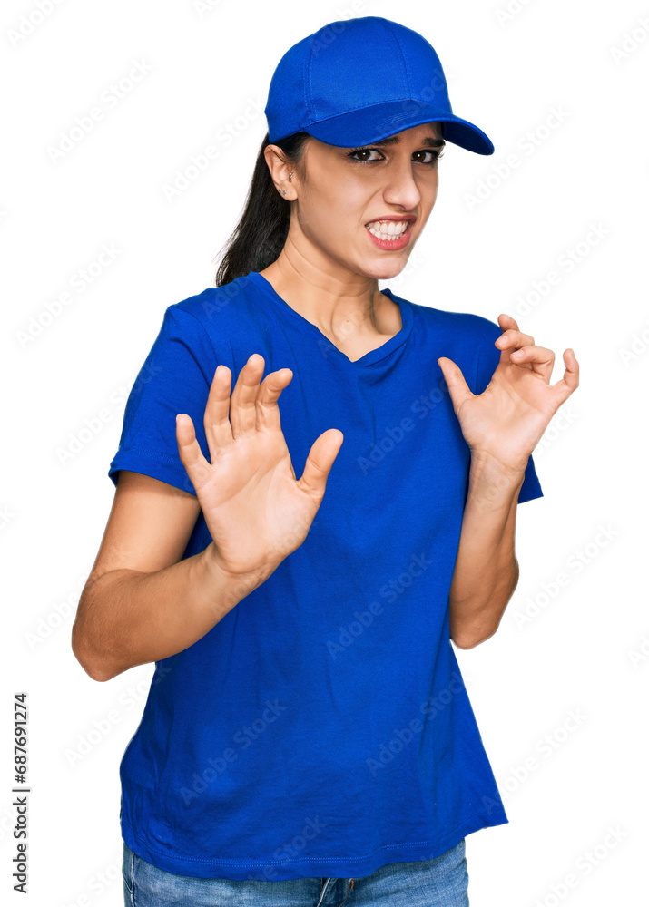 Young hispanic girl wearing delivery courier uniform disgusted expression, displeased and fearful doing disgust face because aversion reaction. with hands raised Young hispanic girl wearing delivery courier uniform disgusted expression, displeased and fearful doing disgust face because aversion reaction. with hands raised