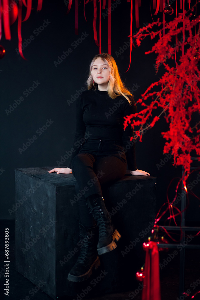 A beautiful young blonde girl in New Year's red clothes in an atmospheric photo studio with a stylish festive interior in red colors. A beautiful young blonde girl in New Year's red clothes in an atmospheric photo studio with a stylish festive interior in red colors.