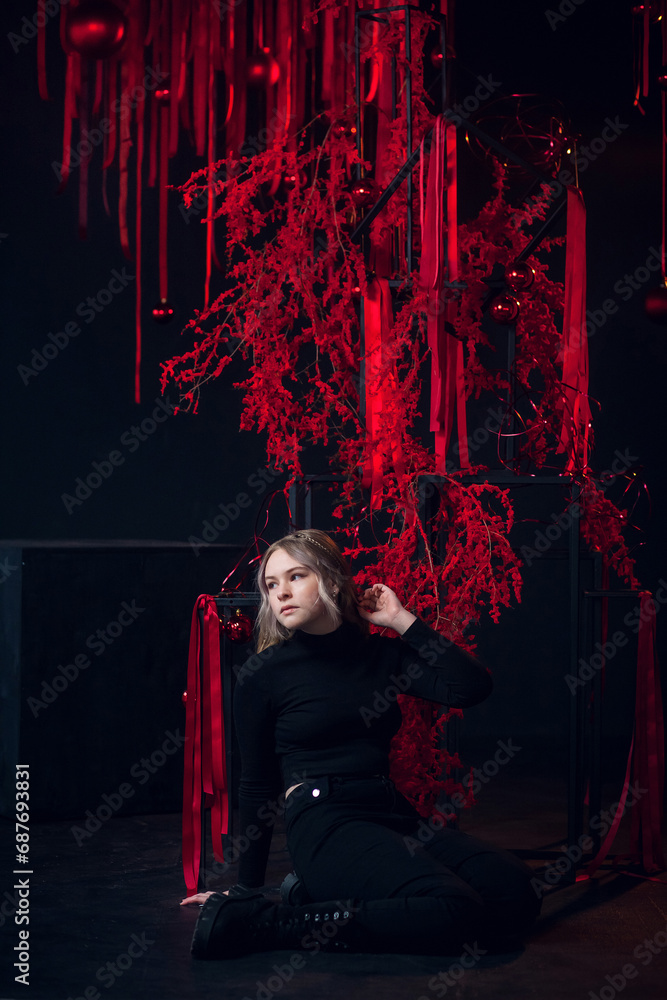 A beautiful young blonde girl in New Year's red clothes in an atmospheric photo studio with a stylish festive interior in red colors. A beautiful young blonde girl in New Year's red clothes in an atmospheric photo studio with a stylish festive interior in red colors.