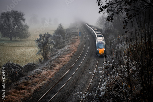 Winter landscape with a train coming out of the fog. Fields covered with frost. View from Dundas Aqueduct, England.
