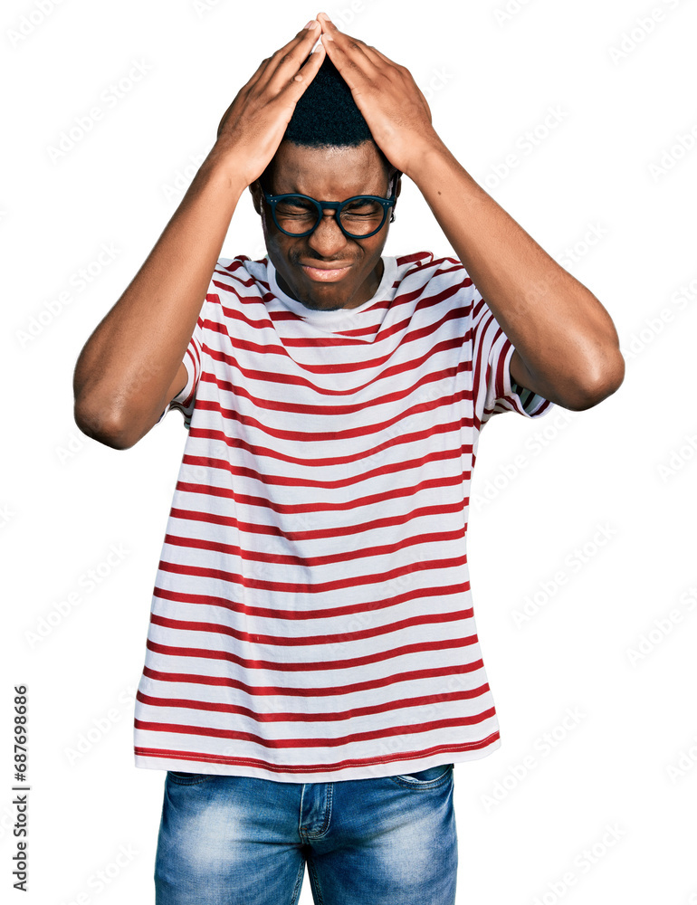 Young african american man wearing casual t shirt and glasses suffering from headache desperate and stressed because pain and migraine. hands on head. Young african american man wearing casual t shirt and glasses suffering from headache desperate and stressed because pain and migraine. hands on head.