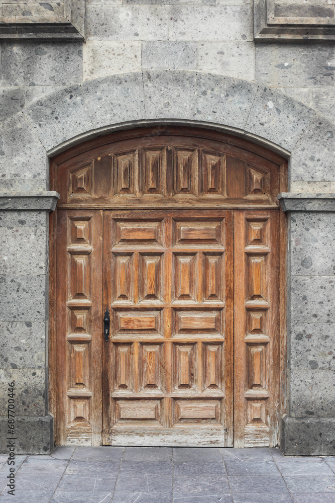 Big wooden door medieval concrete. Wooden door yellow paint wall. Spanish european architecture background. Pavement and street. Urban background. Wooden door house entrance. Retro antique home facade Big wooden door medieval concrete. Wooden door yellow paint wall. Spanish european architecture background. Pavement and street. Urban background. Wooden door house entrance. Retro antique home facade