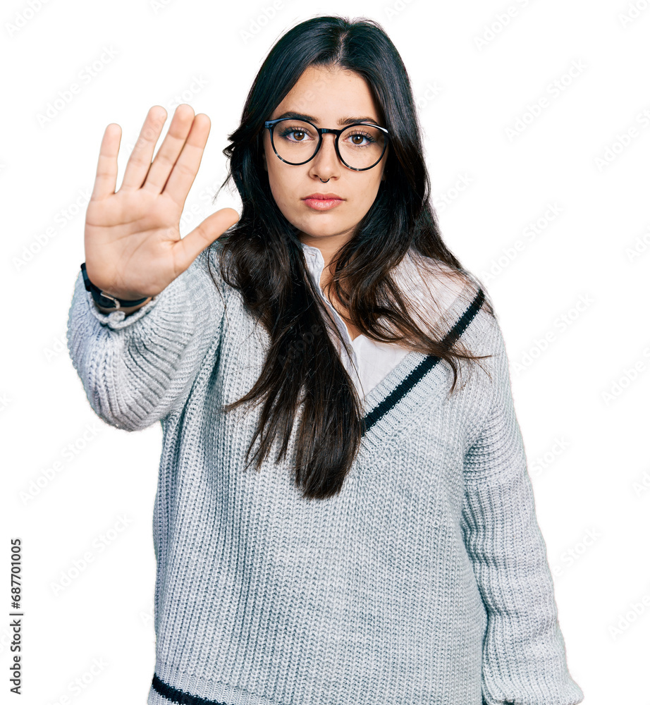 Beautiful hispanic woman wearing casual sweater and glasses doing stop sing with palm of the hand. warning expression with negative and serious gesture on the face. Beautiful hispanic woman wearing casual sweater and glasses doing stop sing with palm of the hand. warning expression with negative and serious gesture on the face.
