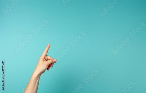 On a vibrant turquoise backdrop, a woman's hand gestures toward an empty space, creating a visually appealing canvas for your text or design