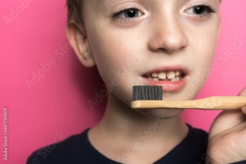 a boy of Slavic appearance holds a bamboo toothbrush in his hands. eco friendly