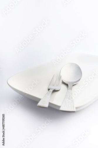 Spoon and fork on white plate on white background, High Key Photography