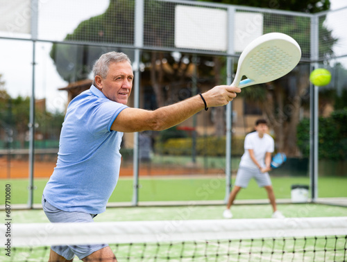 View through the tennis net at an elderly player in the game of padel © JackF