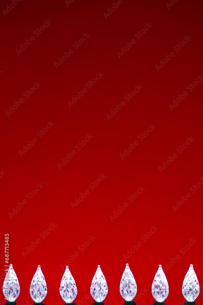 White LED faceted Christmas Lights bottom border against a red verticle background White LED faceted Christmas Lights bottom border against a red verticle background