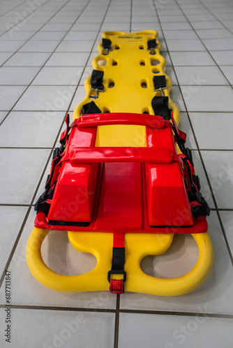 Lifeguard spineboard on white titles in swimming pool