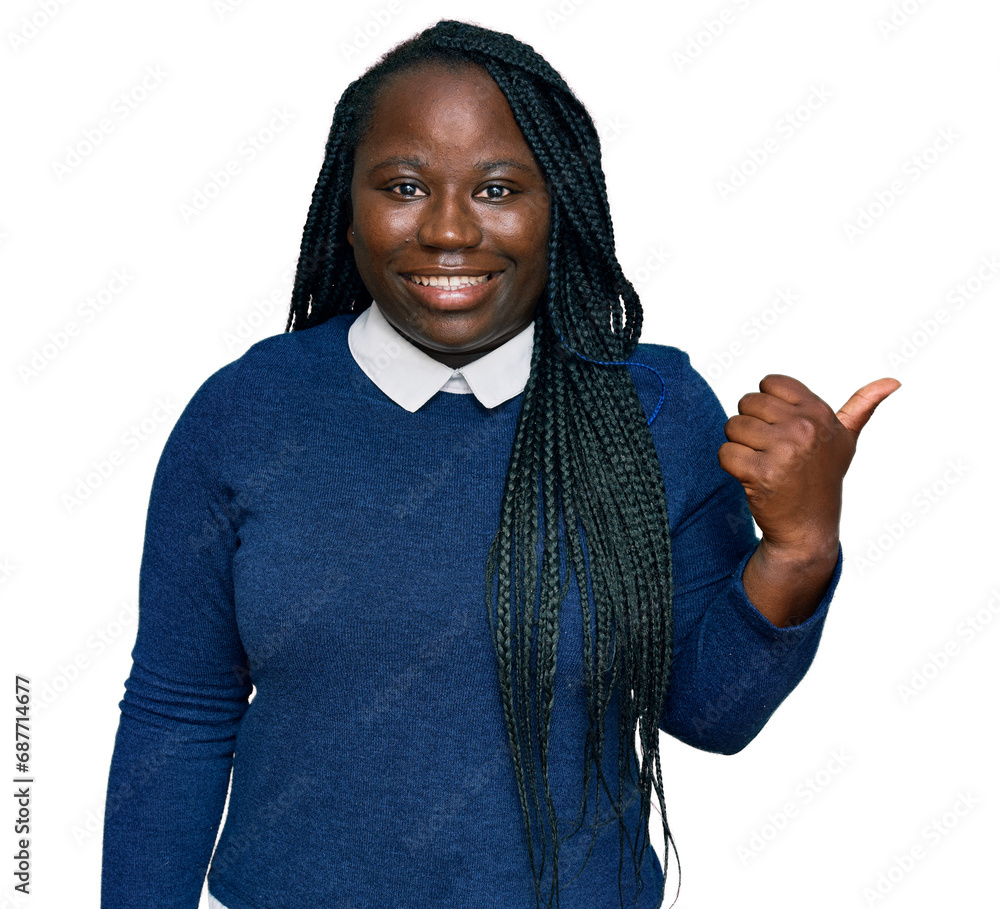 Young black woman with braids wearing casual clothes smiling with happy face looking and pointing to the side with thumb up. Young black woman with braids wearing casual clothes smiling with happy face looking and pointing to the side with thumb up.