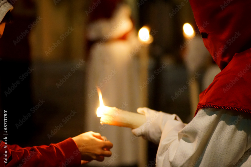 Fototapeta premium A Nazarene giving a candle to a child during Holy Week 