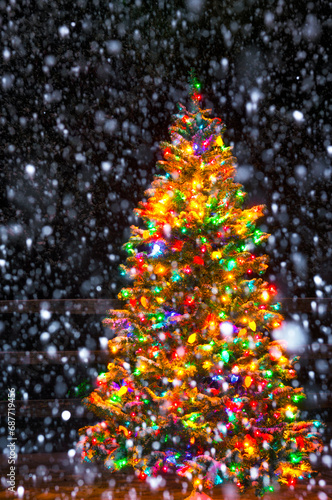 Multi-Colored Christmas tree at night while snowing