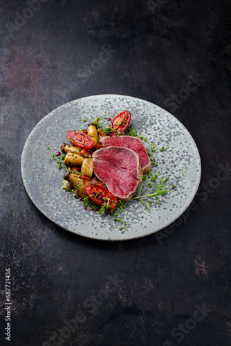 Fried Italian chianina beef fillet steak very rare with mushrooms and tomatoes served as close-up in a Nordic design bowl with copy space