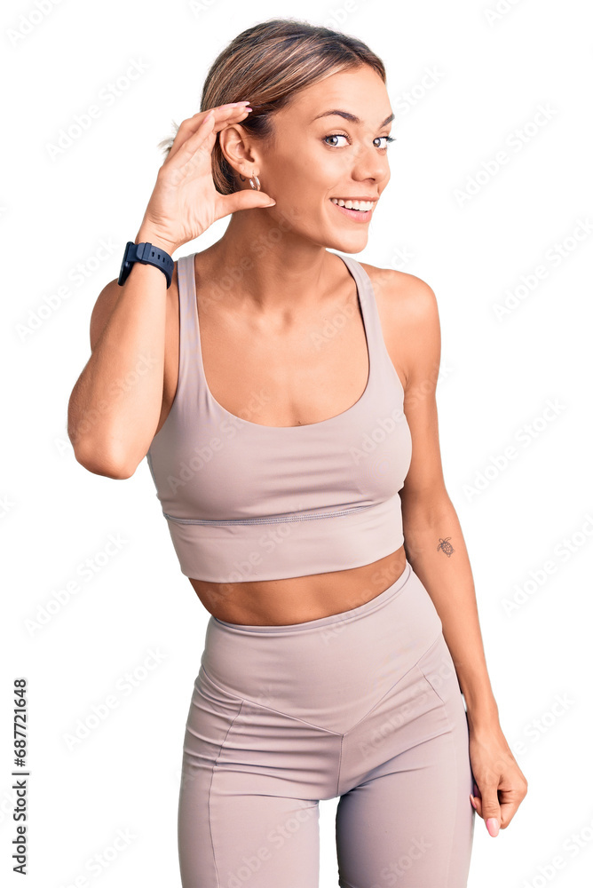 Beautiful caucasian woman wearing sportswear smiling with hand over ear listening an hearing to rumor or gossip. deafness concept. Beautiful caucasian woman wearing sportswear smiling with hand over ear listening an hearing to rumor or gossip. deafness concept.
