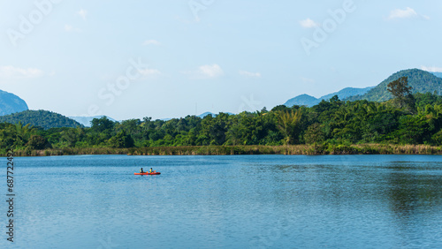 Father and son kayaking on the lake somewhere in Kanchanaburi, Thailand, with beautiful green mountain view.