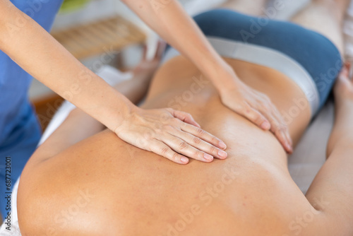 Man receiving massage relax treatment close-up. Masseur hands doing back massage in spa center