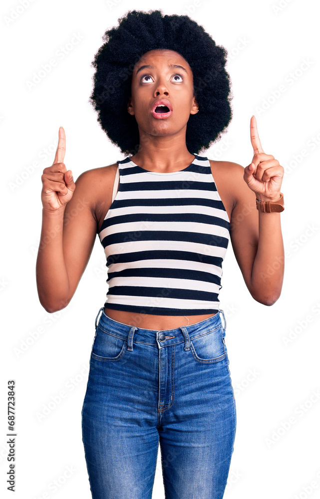Young african american woman wearing casual clothes amazed and surprised looking up and pointing with fingers and raised arms. Young african american woman wearing casual clothes amazed and surprised looking up and pointing with fingers and raised arms.