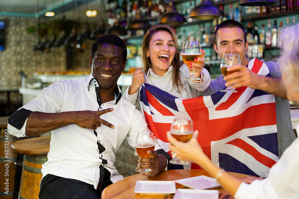 Obraz premium Happy diverse group celebrating Britain at a bar with beer