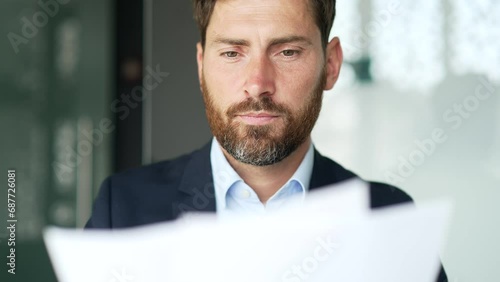 Excited financier in a formal suit is satisfied with results of a financial report he is reviewing sitting at a workplace in a business office. Entrepreneur is happy with positive indicators. Close up photo
