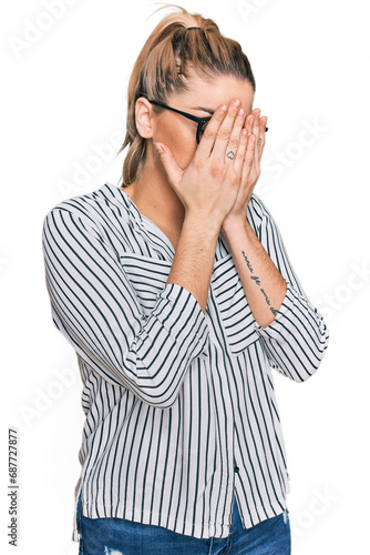 Young caucasian woman wearing business shirt and glasses with sad expression covering face with hands while crying. depression concept.