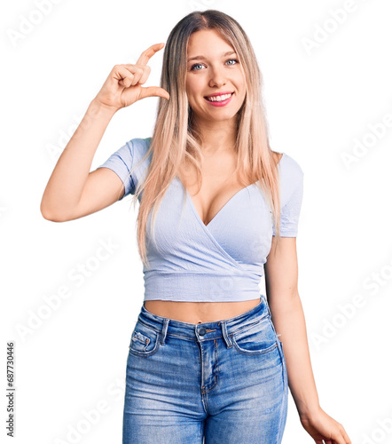 Young beautiful blonde woman wearing casual clothes smiling and confident gesturing with hand doing small size sign with fingers looking and the camera. measure concept.