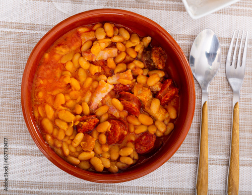 Appetizing bean stew served on plate with pieces of chorizo sausage..