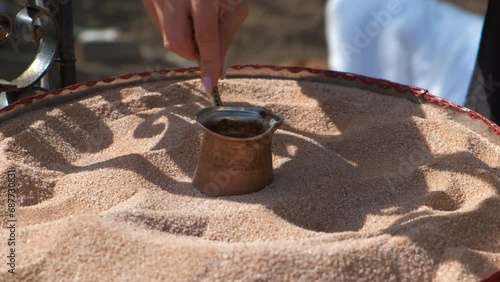 Cooking turkish coffee in city. A view of man hand cooking coffee on the hot sand in the urban place during day time. photo