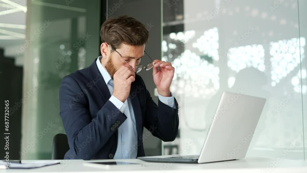 Overworked businessman in formal suit suffering from eye strain and headache working on laptop at workplace in business office. Tired entrepreneur takes off glasses and massages, rubs bridge of nose Overworked businessman in formal suit suffering from eye strain and headache working on laptop at workplace in business office. Tired entrepreneur takes off glasses and massages, rubs bridge of nose