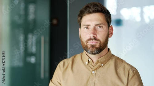 Portrait of serious handsome manager in shirt standing at workplace in modern business office. Confident bearded worker posing looking at camera indoors. Head shot of a thoughtful tutor. Close up photo