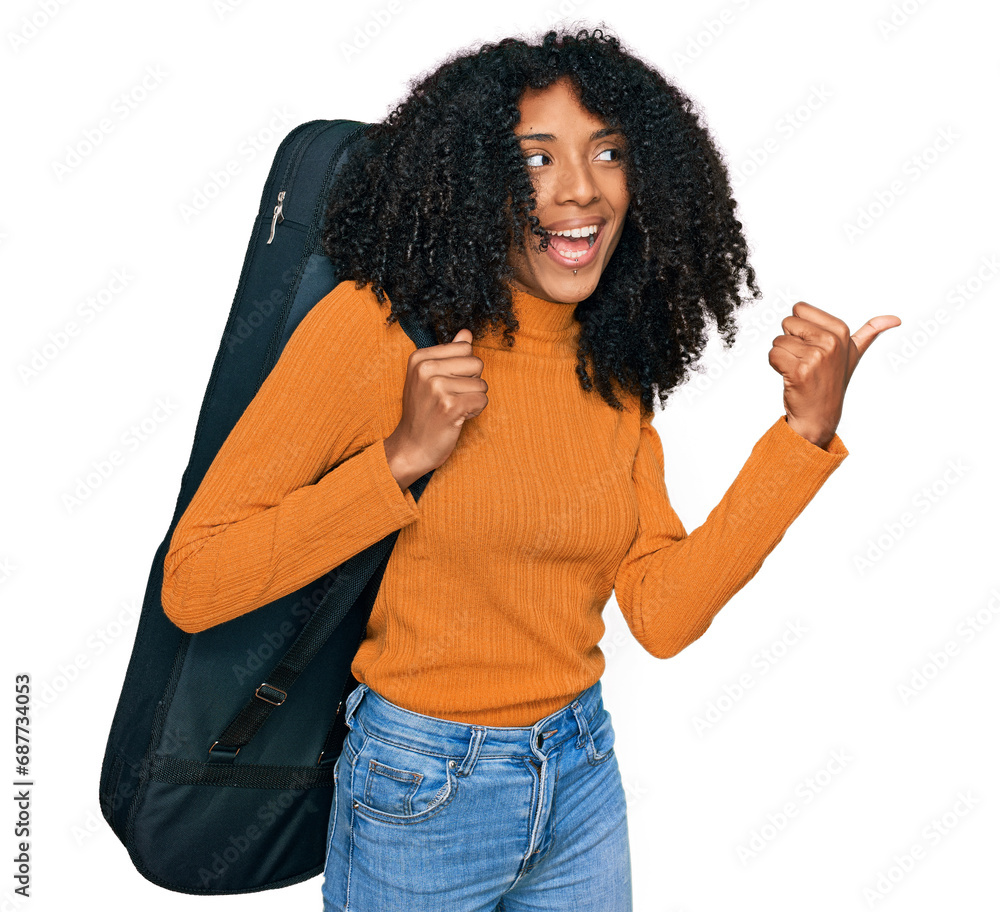 Young african american girl wearing guitar case pointing thumb up to the side smiling happy with open mouth Young african american girl wearing guitar case pointing thumb up to the side smiling happy with open mouth
