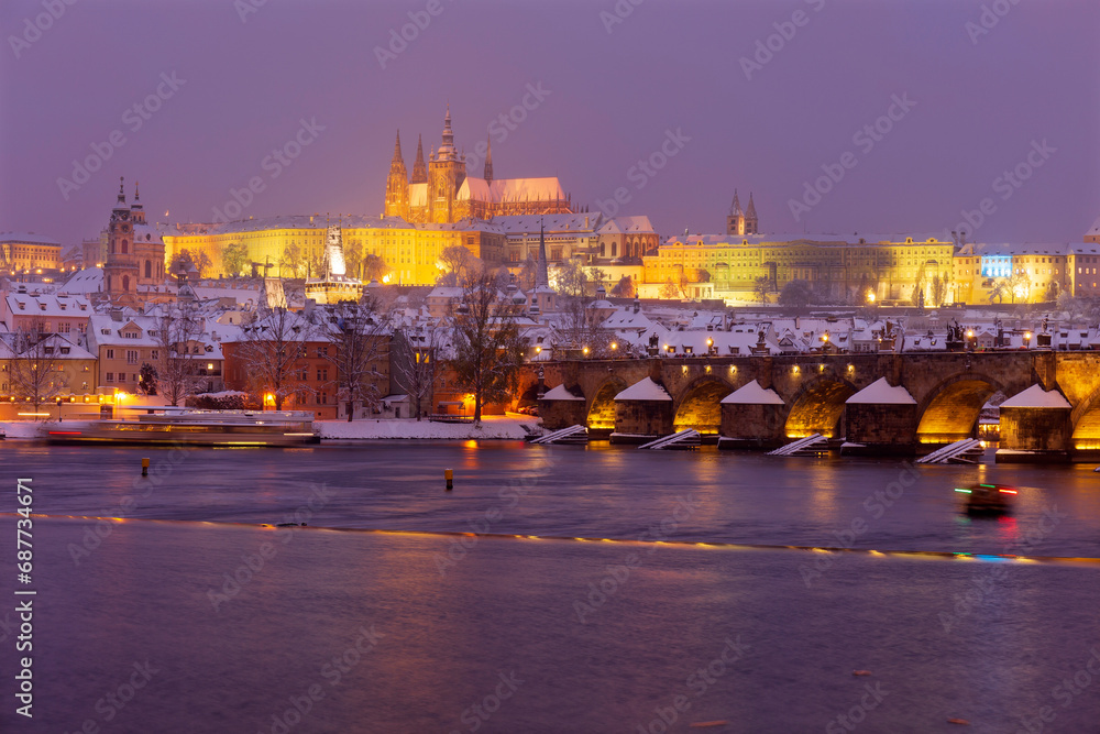 The night snowy Prague Lesser Town with gothic Castle and Charles Bridge above River Vltava, Czech Republic