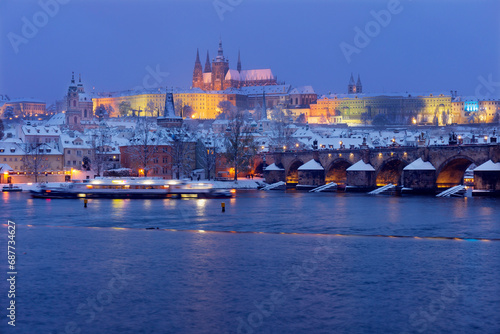 The night snowy Prague Lesser Town with gothic Castle and Charles Bridge above River Vltava  Czech Republic