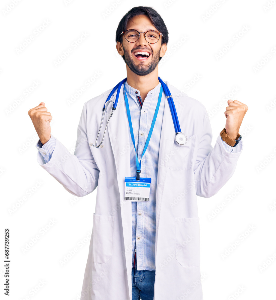 Handsome hispanic man wearing doctor uniform and stethoscope screaming proud, celebrating victory and success very excited with raised arms