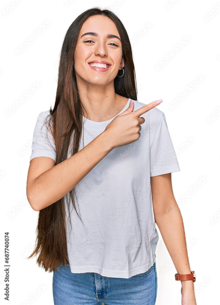 Young hispanic girl wearing casual white t shirt cheerful with a smile on face pointing with hand and finger up to the side with happy and natural expression Young hispanic girl wearing casual white t shirt cheerful with a smile on face pointing with hand and finger up to the side with happy and natural expression