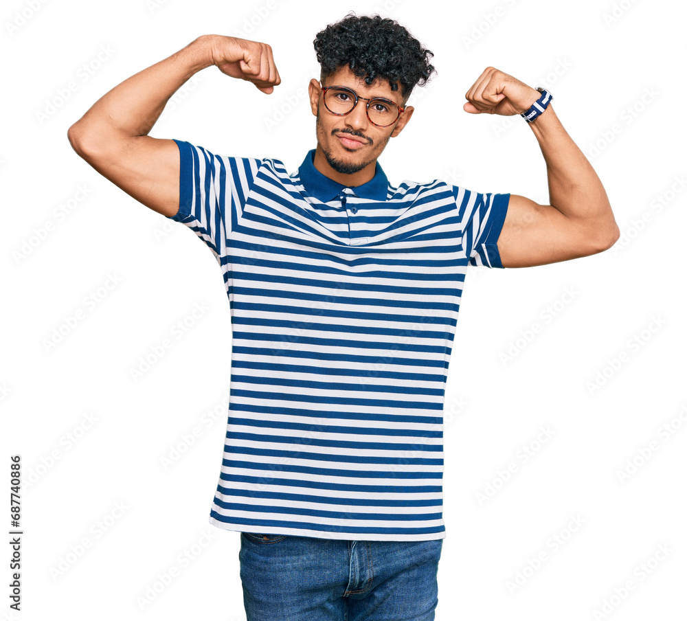 Young arab man wearing casual clothes and glasses showing arms muscles smiling proud. fitness concept. Young arab man wearing casual clothes and glasses showing arms muscles smiling proud. fitness concept.