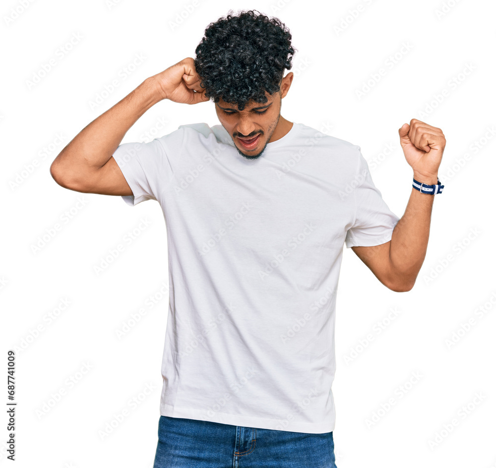 Young arab man wearing casual white t shirt dancing happy and cheerful, smiling moving casual and confident listening to music Young arab man wearing casual white t shirt dancing happy and cheerful, smiling moving casual and confident listening to music