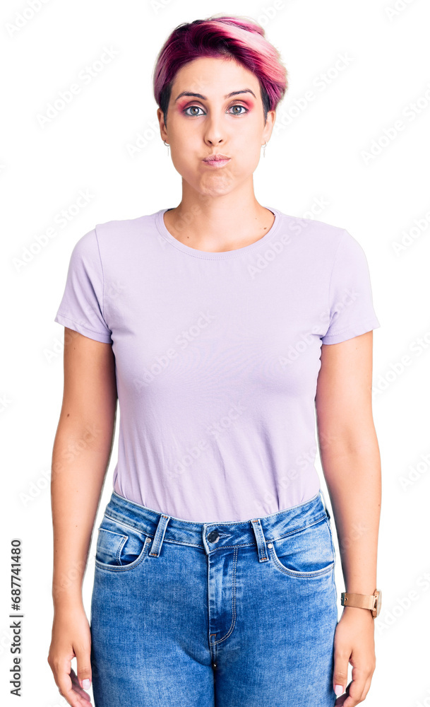 Young beautiful woman with pink hair wearing casual clothes puffing cheeks with funny face. mouth inflated with air, crazy expression. Young beautiful woman with pink hair wearing casual clothes puffing cheeks with funny face. mouth inflated with air, crazy expression.