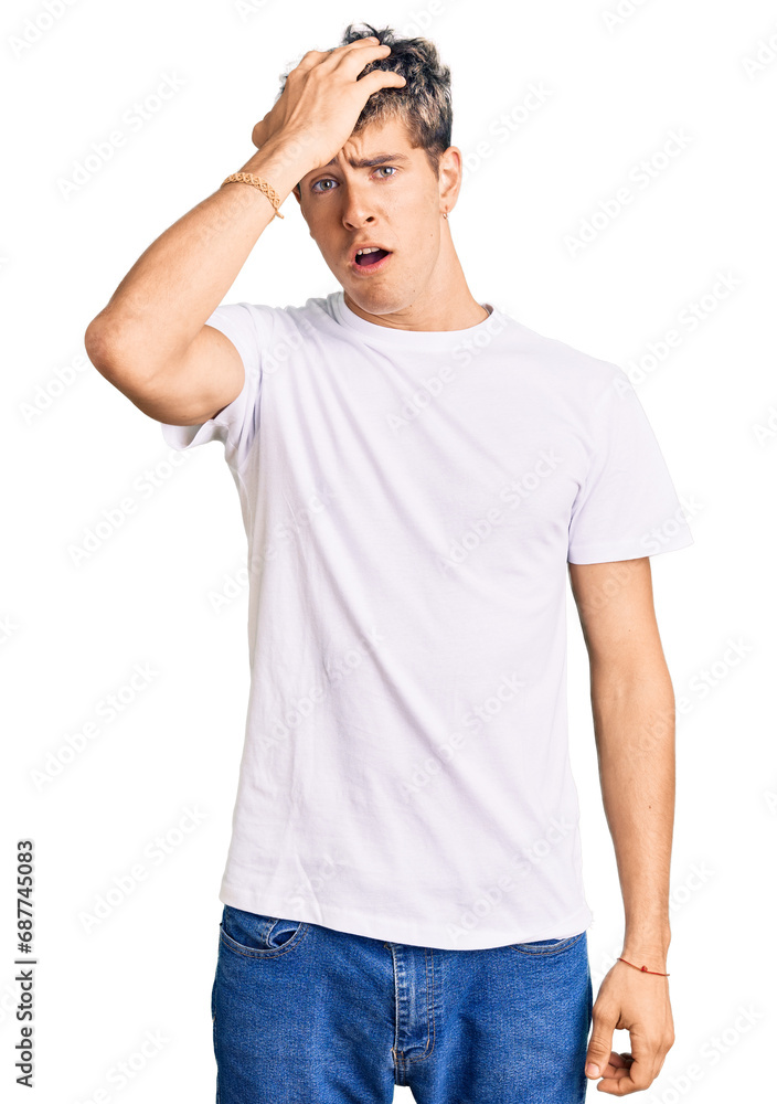 Fototapeta premium Young handsome man wearing casual white tshirt surprised with hand on head for mistake, remember error. forgot, bad memory concept.
