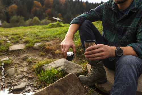 Man with thermo tumbler in nature, closeup. Space for text photo