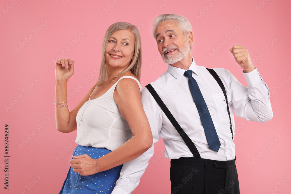 Senior couple dancing together on pink background Senior couple dancing together on pink background