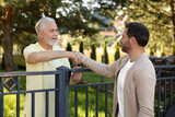Friendly relationship with neighbours. Happy men shaking hands above fence outdoors