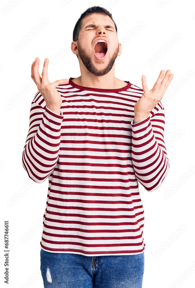 Young handsome man wearing striped sweater celebrating mad and crazy for success with arms raised and closed eyes screaming excited. winner concept Young handsome man wearing striped sweater celebrating mad and crazy for success with arms raised and closed eyes screaming excited. winner concept