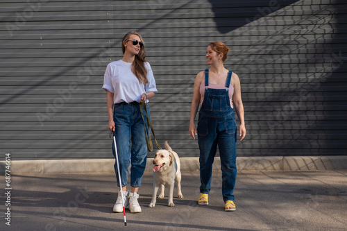 Blind caucasian woman walking with guide dog and pregnant girlfriend. 