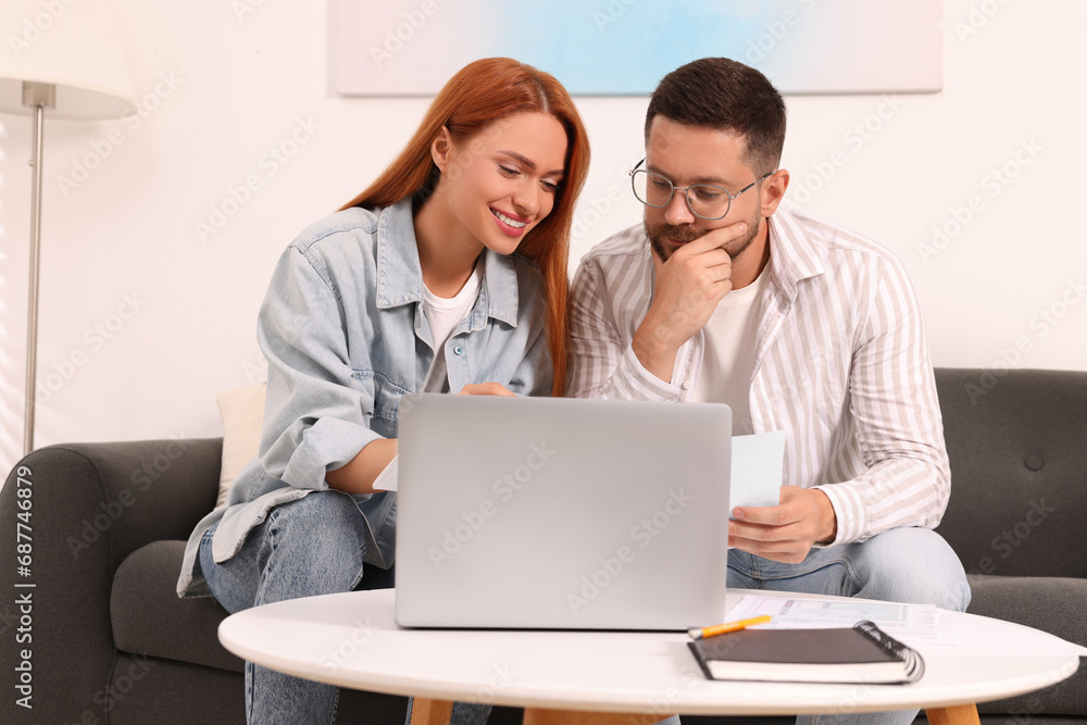 Couple doing taxes at table in living room Couple doing taxes at table in living room