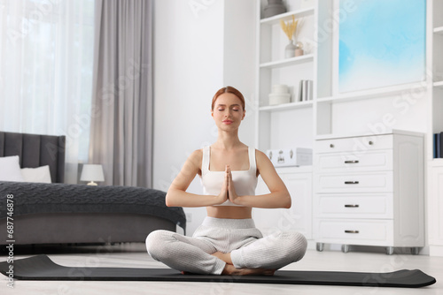 Beautiful young woman practicing Padmasana on yoga mat at home. Lotus pose Free Download Beautiful young woman practicing Padmasana on yoga mat at home. Lotus pose - GFXLoad