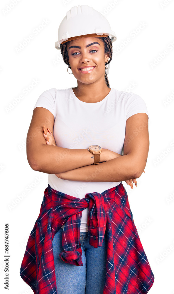 Young african american woman with braids wearing hardhat and builder clothes happy face smiling with crossed arms looking at the camera. positive person. Young african american woman with braids wearing hardhat and builder clothes happy face smiling with crossed arms looking at the camera. positive person.