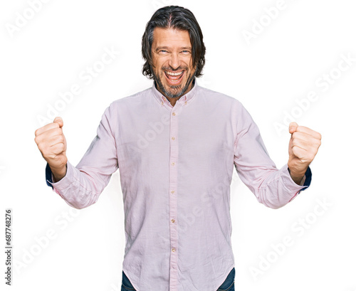 Middle age handsome man wearing business shirt very happy and excited doing winner gesture with arms raised, smiling and screaming for success. celebration concept.