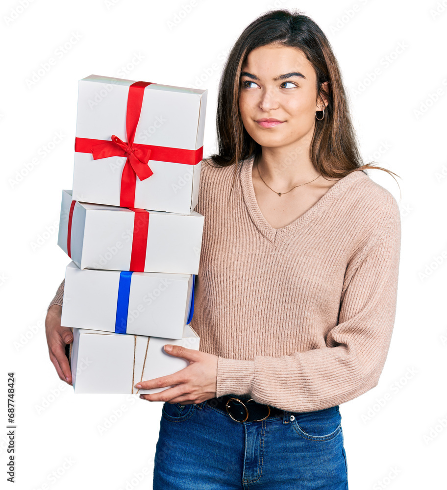 Young caucasian girl holding gifts smiling looking to the side and staring away thinking. Young caucasian girl holding gifts smiling looking to the side and staring away thinking.