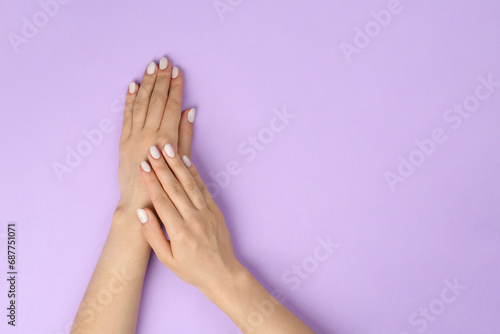 Woman with white polish on nails against violet background  top view. Space for text