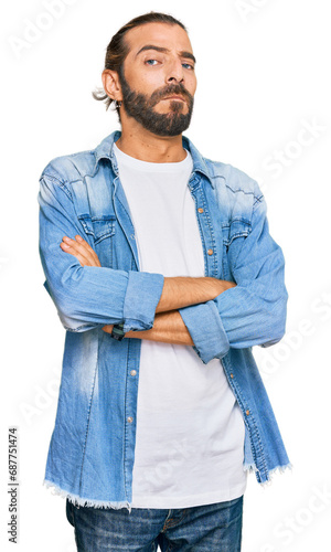 Attractive man with long hair and beard wearing casual denim jacket skeptic and nervous, disapproving expression on face with crossed arms. negative person.